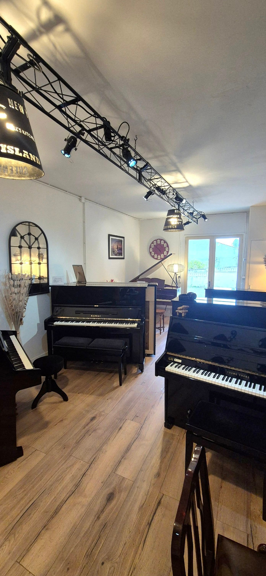 Intérieur du showroom Pianos d'Occitanie avec pianos droits Kawai et Young Chang
